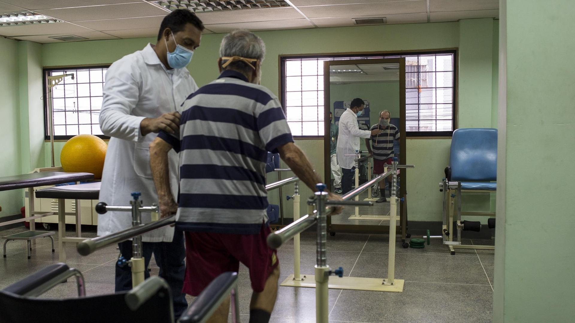 Der 78-jährige Eduardo Ortiz (l) macht Übungen mit Fachkräften eines von der Regierung betriebenen Reha-Zentrums für Covid-19-Patienten in Venezuela. Der 78-jährige Eduardo Ortiz (l) macht Übungen mit Fachkräften eines von der Regierung betriebenen Reha-Zentrums für Covid-19-Patienten in Venezuela.