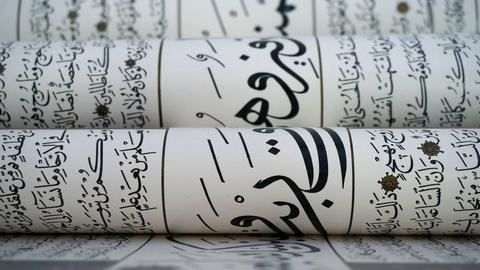 Mehrere Bögen mit arabischer Kalligrafie liegen übereinander.