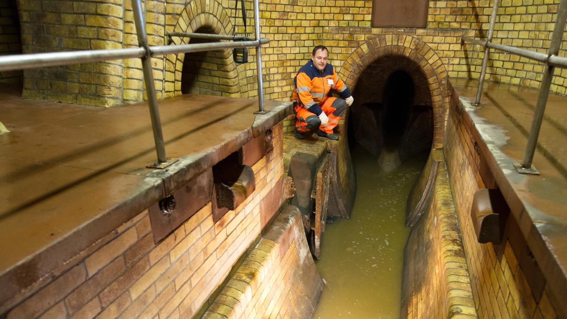 Ein Kanalarbeiter steht während einer öffentlichen Führung durch die Kanalisation an einem Abwasserkanal Ein Kanalarbeiter steht während einer öffentlichen Führung durch die Kanalisation an einem Abwasserkanal