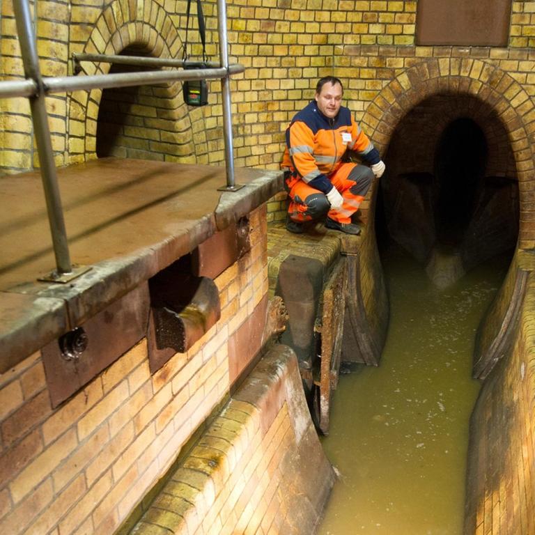 Ein Kanalarbeiter steht während einer öffentlichen Führung durch die Kanalisation an einem Abwasserkanal