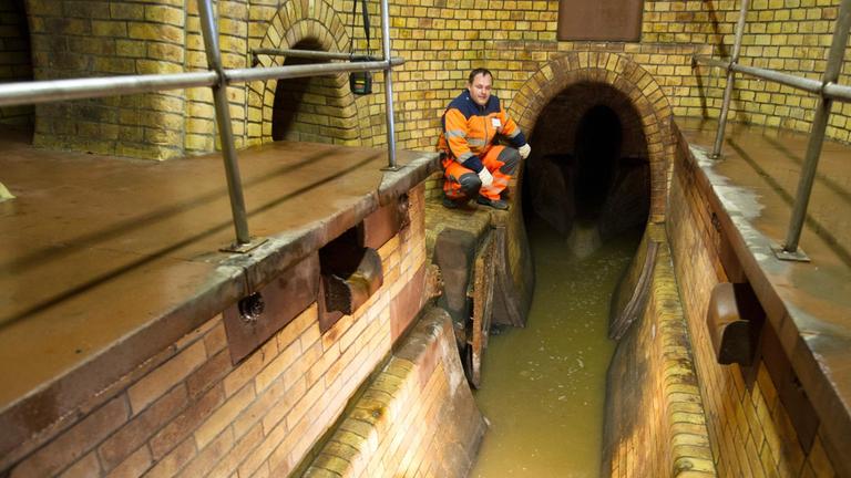 Ein Kanalarbeiter steht während einer öffentlichen Führung durch die Kanalisation an einem Abwasserkanal