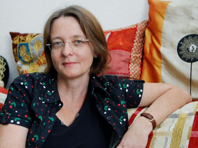 Die Schriftstellerin Grit Poppe auf einem Sofa mit bunt gemusterten Kissen.