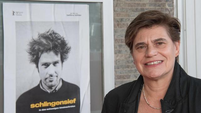 Bettina Böhler neben dem Plakat des Filmes "Schlingensief – In das Schweigen hineinschreien""