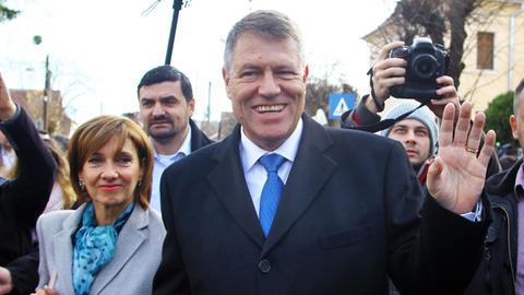 Der siegreiche Präsidentschaftskandidat Klaus Johannis verlässt mit seiner Frau ein Wahllokal und ist dabei umringt von Fotografen.