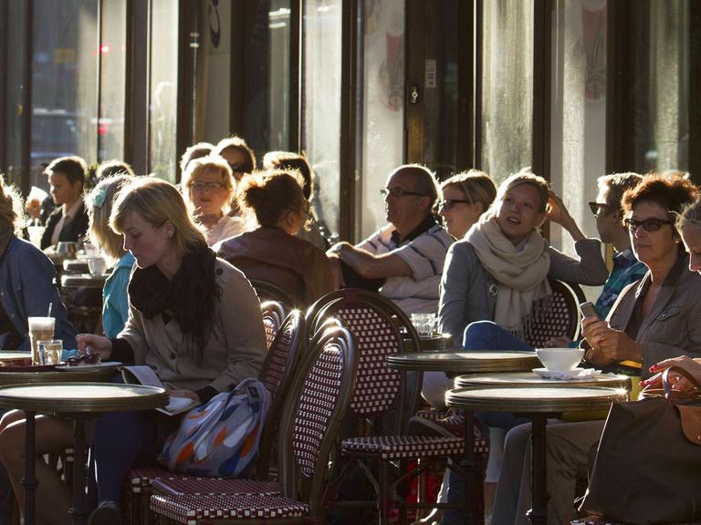 Menschen sitzen in einem Straßencafe in der finnischen Hauptstadt Helsinki