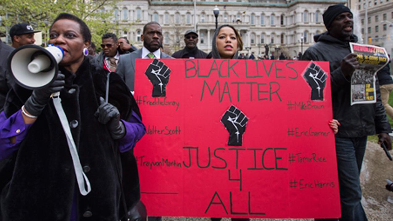 Demonstranten in Baltimore halten ein Schild hoch, auf dem steht: "Justice for all" Demonstranten in Baltimore halten ein Schild hoch, auf dem steht: "Justice for all"