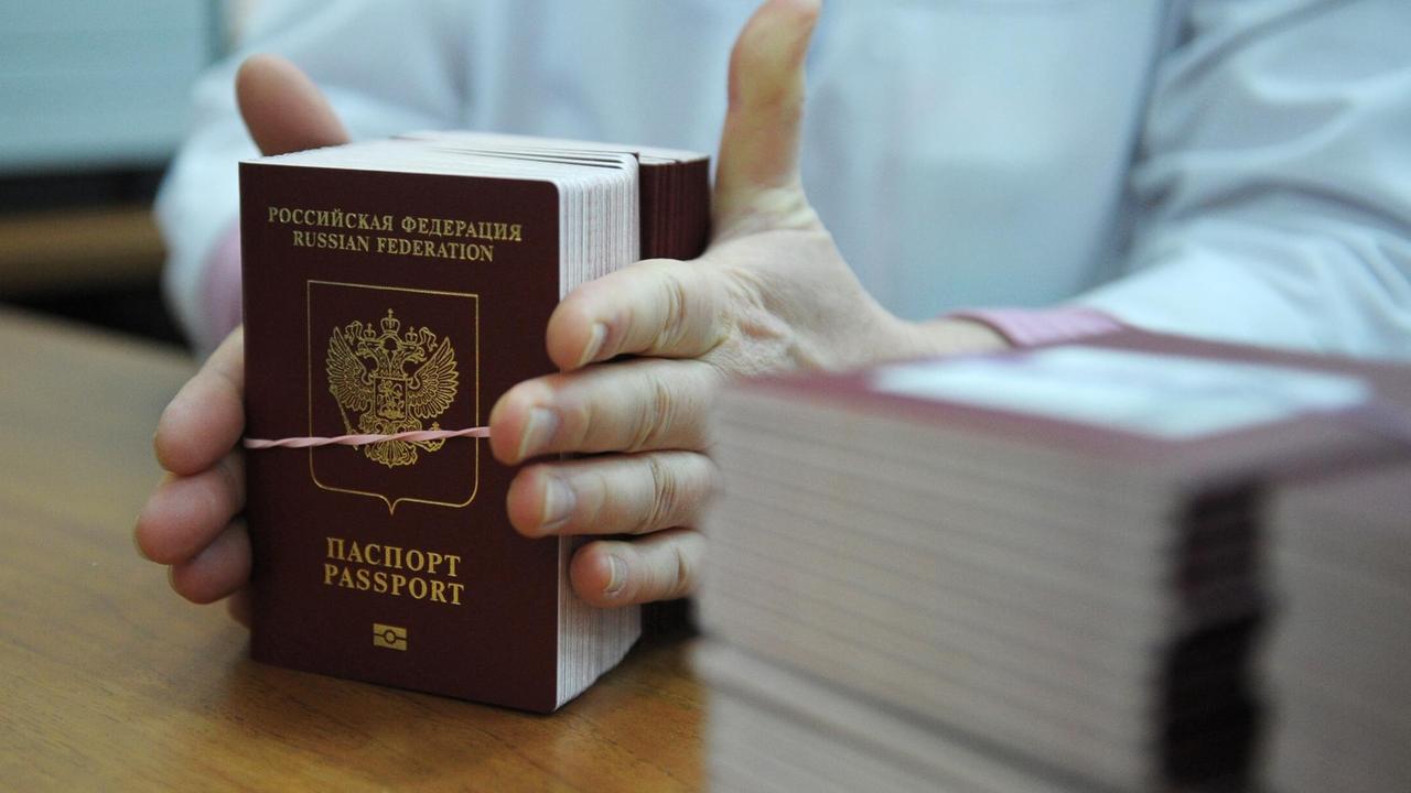 Eine Hand hält einen Stapel russische Pässe. Eine Hand hält einen Stapel russische Pässe.