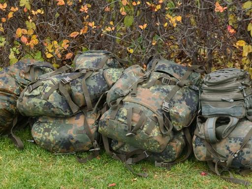Ein Haufen Rucksäcke von Bundeswehrsoldaten liegt auf einer Wiese.