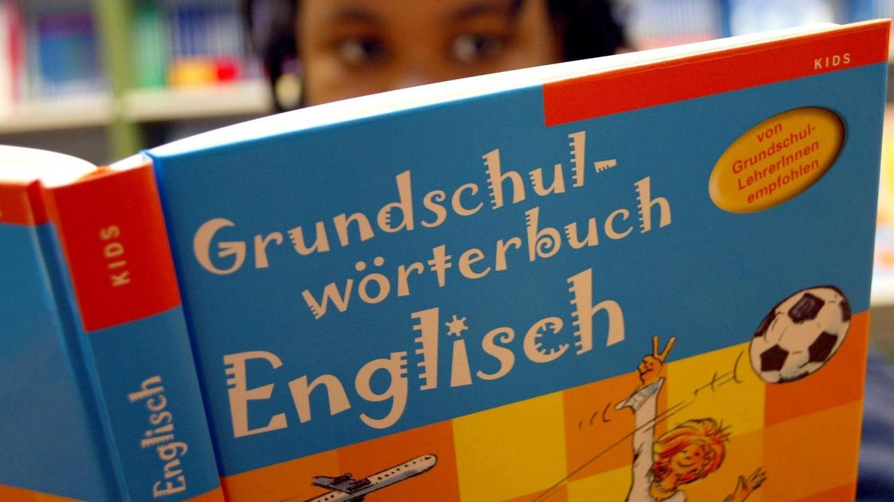 Sie sehen ein Mädchen, das in einem Englischbuch für die Grundschule liest. Sie sehen ein Mädchen, das in einem Englischbuch für die Grundschule liest.