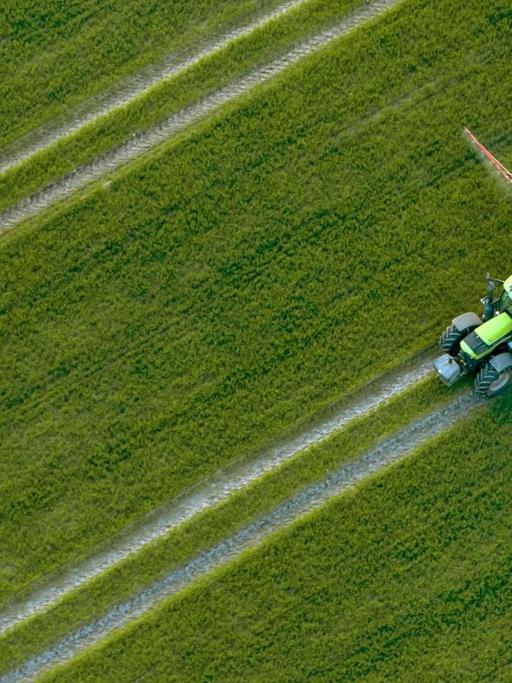 Luftaufnahme eines Traktors, der Pestizide über ein Feld versprüht