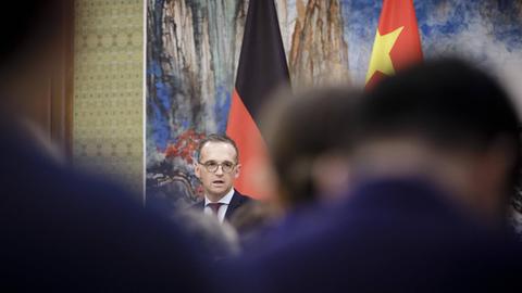 Bundesaußenminister Heiko Maas (SPD) vor der deutschen und der chinesischen Flagge - im Vordergrund sind Rücken von Zuhörenden zu sehen, aufgenommen im November 2018