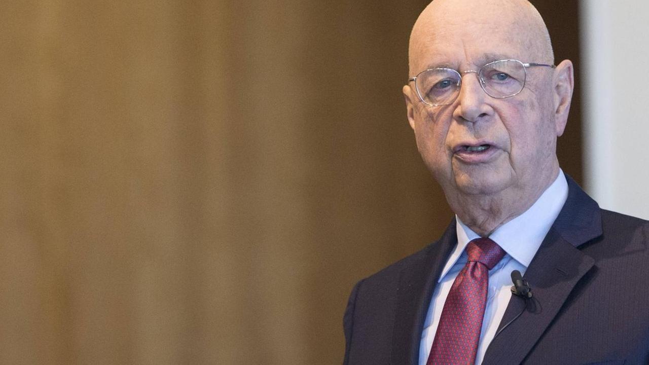 Klaus Schwab, ein älterer Herr, im seriösen Anzug vor einer vertäfelten Wand. Klaus Schwab, ein älterer Herr, im seriösen Anzug vor einer vertäfelten Wand.