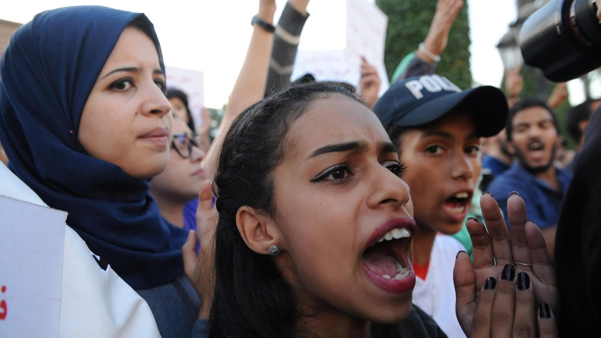 In Marokkos Hauptstadt Rabat demonstrieren zwei junge Frauen und ein junger Mann mit Schirmmütze gegen den gewaltsamen Tod eines Fischers. In Marokkos Hauptstadt Rabat demonstrieren zwei junge Frauen und ein junger Mann mit Schirmmütze gegen den gewaltsamen Tod eines Fischers.