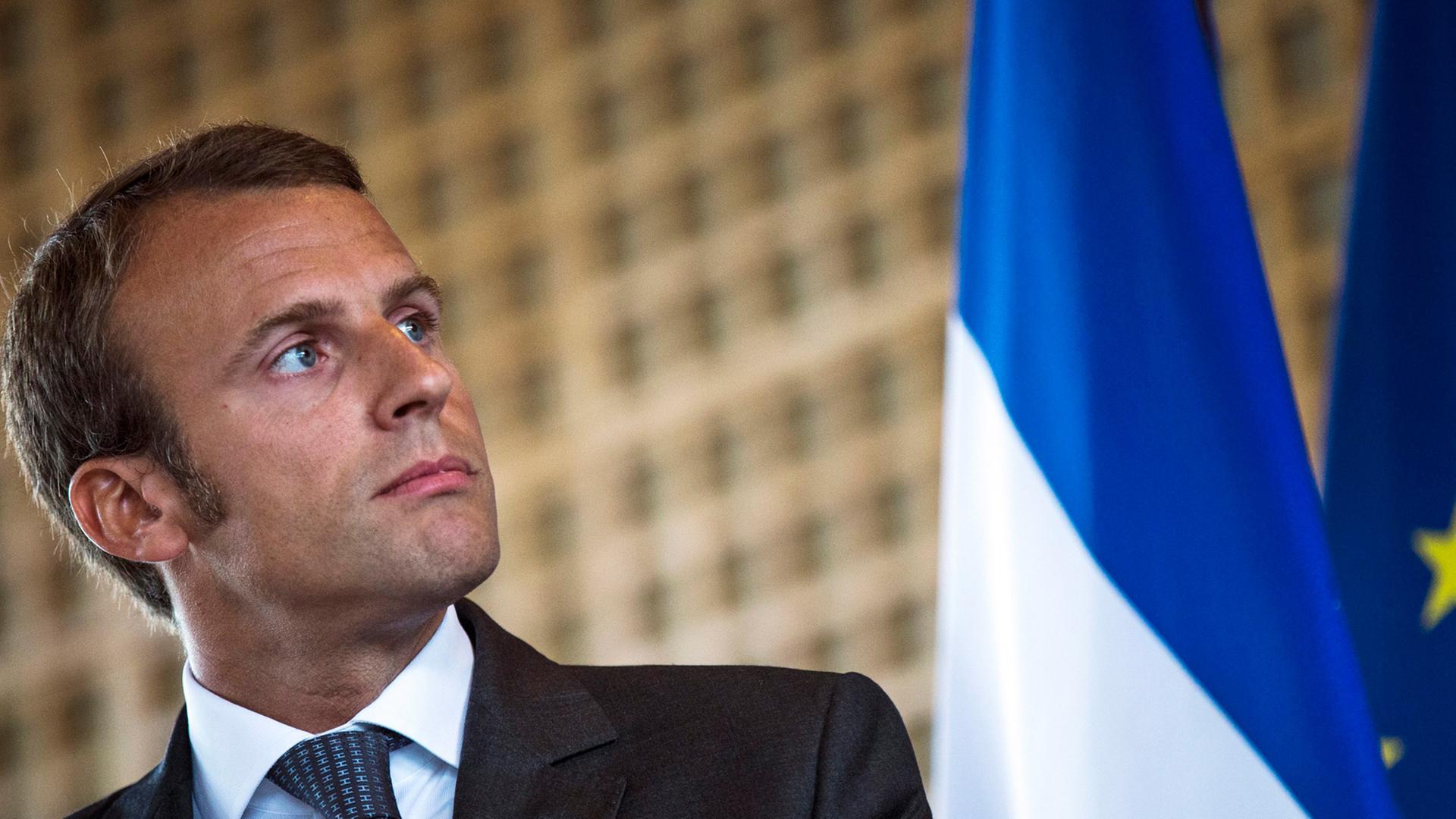 Frankreichs Wirtschaftminister Emmanuel Macron, im Hintergrund eine Fahne Frankreichs Wirtschaftminister Emmanuel Macron, im Hintergrund eine Fahne