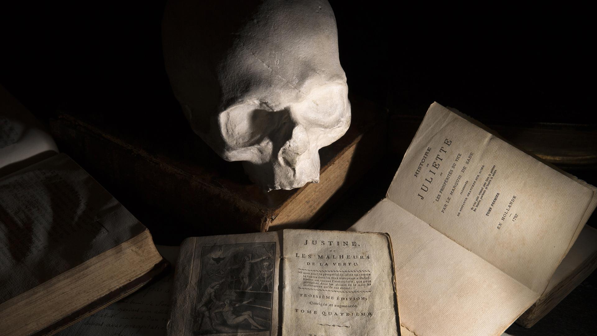 Ein Gipsabdruck des Totenschädels des Marquis de Sade ist neben älteren Ausgaben der Werke "Justine" (1801), "Juliette" (1797) und "L'union des arts ou les ruses de l'amour" (1810) zu sehen. Ein Gipsabdruck des Totenschädels des Marquis de Sade ist neben älteren Ausgaben der Werke "Justine" (1801), "Juliette" (1797) und "L'union des arts ou les ruses de l'amour" (1810) zu sehen.