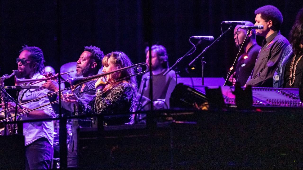 Drei Musiker mit Blasinstrumenten und drei Sänger stehen auf einer Bühne und spielen Musik. Drei Musiker mit Blasinstrumenten und drei Sänger stehen auf einer Bühne und spielen Musik.