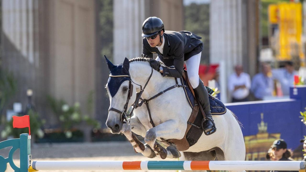 Marcell Marschall springt auf seinem Pferd über ein Hindernis beim Championat Global Jumping im Juli in Berlin. Im Hintergrund sind in der Unschärfe die Säulen des Brandenburger Tors zu sehen. Marcell Marschall springt auf seinem Pferd über ein Hindernis beim Championat Global Jumping im Juli in Berlin. Im Hintergrund sind in der Unschärfe die Säulen des Brandenburger Tors zu sehen.