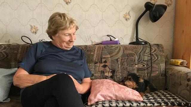 Paulina Zerluk sitzt zu Hause in Koblenz auf ihrem Sofa, neben ihr Hund Knopka