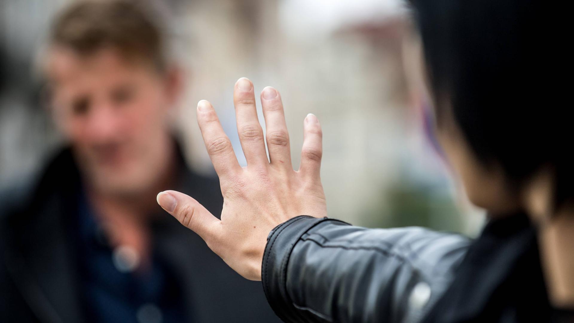 Eine Frau wehrt mit ausgestrecktem Arm einen Mann ab. Eine Frau wehrt mit ausgestrecktem Arm einen Mann ab.