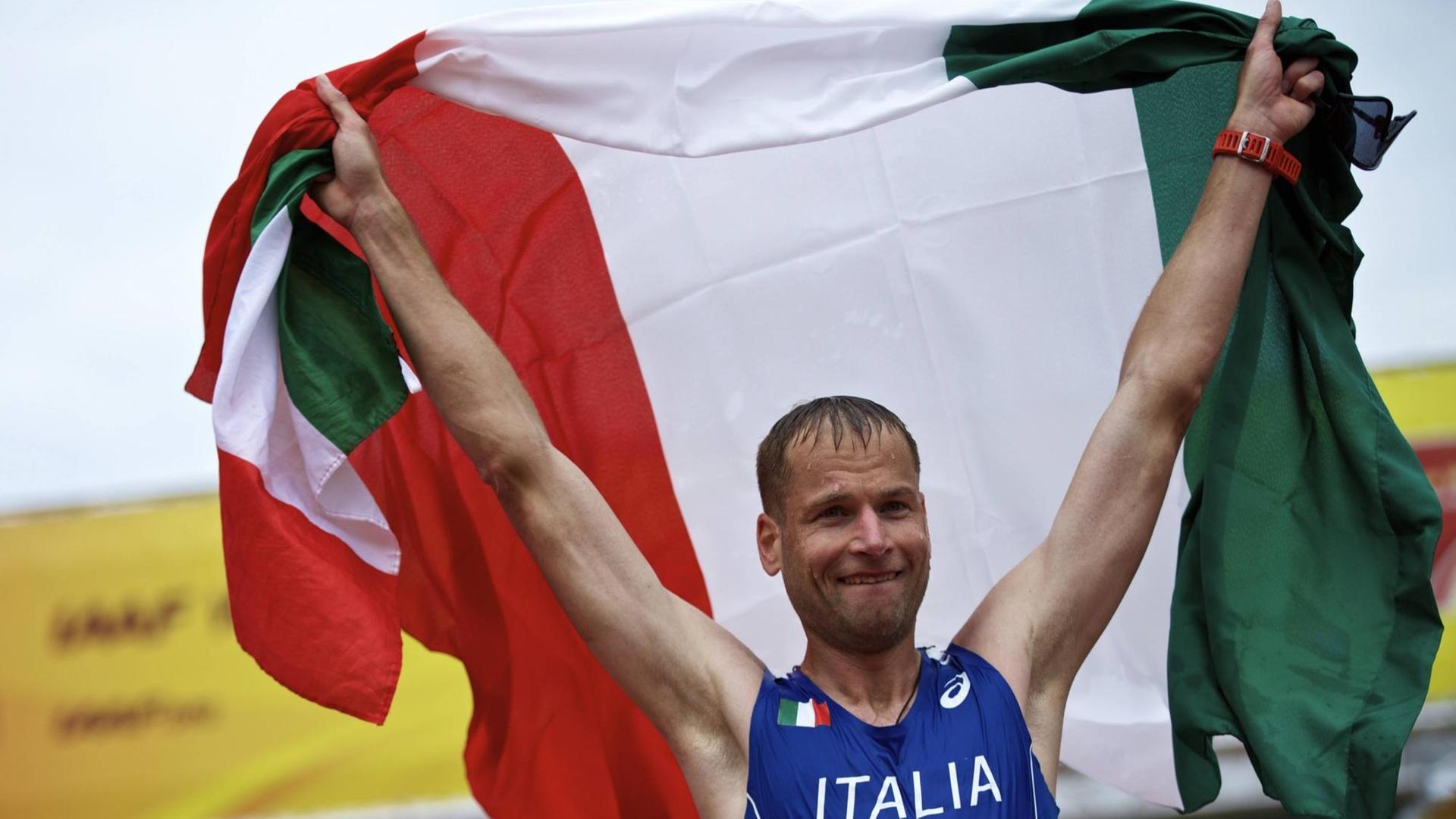 Alex Schwazer hält die italienische Fahne über seinen Kopf. Alex Schwazer hält die italienische Fahne über seinen Kopf.