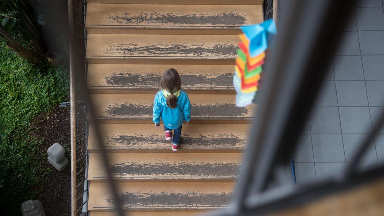 Ein Mädchen geht eine Schultreppe hinauf, von der der Farbe abblättert. Ein Mädchen geht eine Schultreppe hinauf, von der der Farbe abblättert.