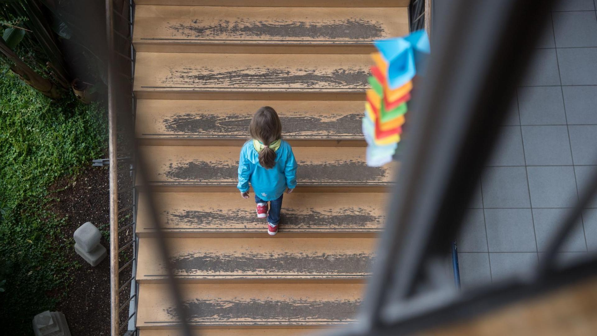 Ein Mädchen geht eine Schultreppe hinauf, von der der Farbe abblättert. Ein Mädchen geht eine Schultreppe hinauf, von der der Farbe abblättert.