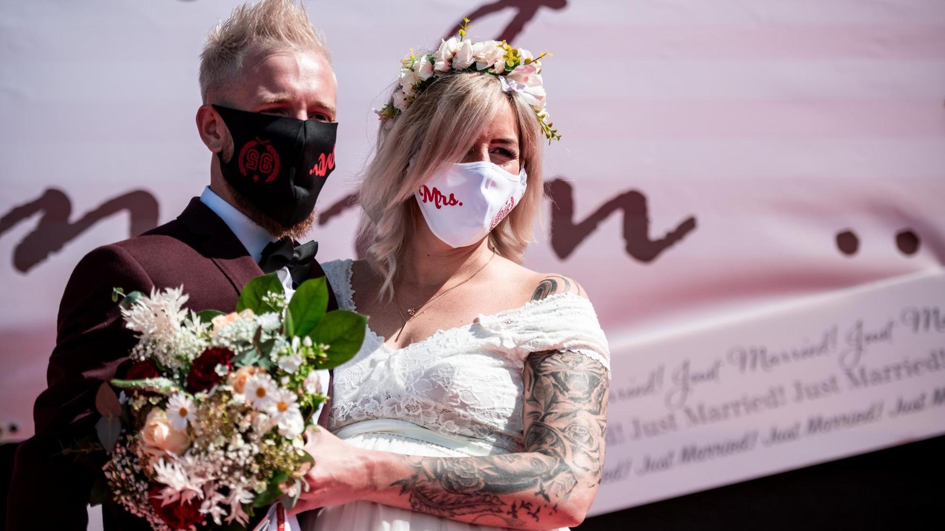 Das Brautpaar Janine und Philip Scholz steht bei der Trauung im Autokino mit Mundschutz vor der Bühne. Das Brautpaar Janine und Philip Scholz steht bei der Trauung im Autokino mit Mundschutz vor der Bühne.