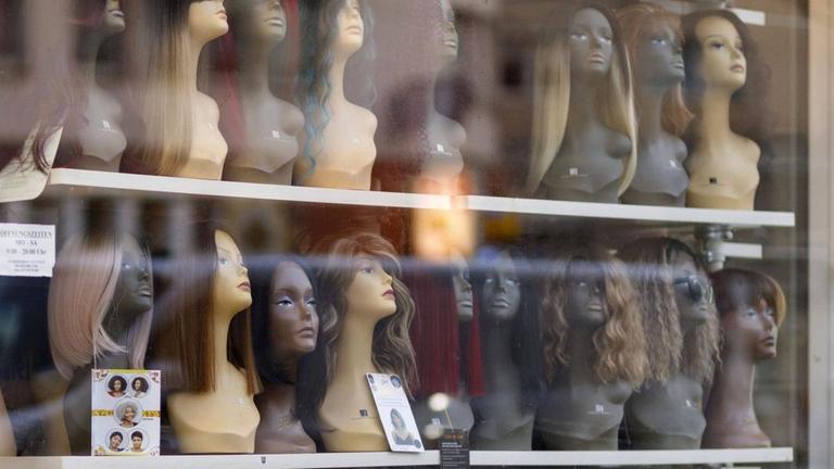In einem Schaufenster stehen dicht an dicht Schaufensterpuppen mit Perücken In einem Schaufenster stehen dicht an dicht Schaufensterpuppen mit Perücken