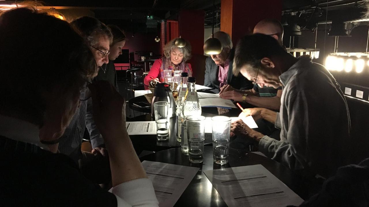Menschen sitzen über Fragegebogen gebeugt an einem Cafétisch. Menschen sitzen über Fragegebogen gebeugt an einem Cafétisch.