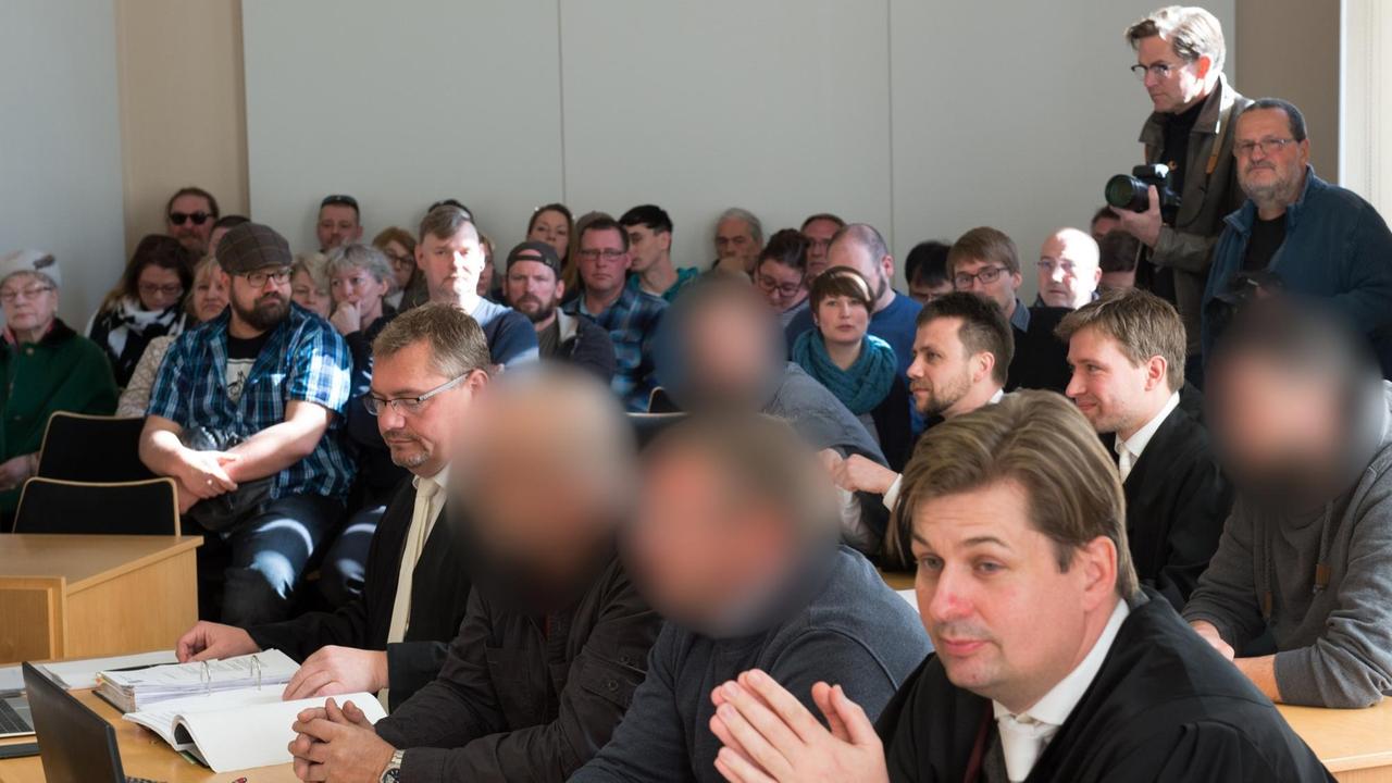 Vier angeklagten Männer (erste Reihe 2. und 3. v.l. und zweite Reihe 1. und 4. v.l.) haben am 24.04.2017 im Amtsgericht in Kamenz (Sachsen) neben ihren Anwälten ihre Plätze eingenommen. Knapp ein Jahr nachdem sie einen psychisch kranken Flüchtling aus einem Supermarkt gezerrt und an einen Baum gefesselt haben sollen, müssen sich die vier Männer vor Gericht verantworten. Den Angeklagten im Alter zwischen 29 und 56 Jahren wird Freiheitsberaubung vorgeworfen. Sie weisen die Schuld von sich und behaupten, dass der Iraker eine Kassiererin des Supermarktes in Arnsdorf (Kreis Bautzen) bedroht habe. Vier angeklagten Männer (erste Reihe 2. und 3. v.l. und zweite Reihe 1. und 4. v.l.) haben am 24.04.2017 im Amtsgericht in Kamenz (Sachsen) neben ihren Anwälten ihre Plätze eingenommen. Knapp ein Jahr nachdem sie einen psychisch kranken Flüchtling aus einem Supermarkt gezerrt und an einen Baum gefesselt haben sollen, müssen sich die vier Männer vor Gericht verantworten. Den Angeklagten im Alter zwischen 29 und 56 Jahren wird Freiheitsberaubung vorgeworfen. Sie weisen die Schuld von sich und behaupten, dass der Iraker eine Kassiererin des Supermarktes in Arnsdorf (Kreis Bautzen) bedroht habe.