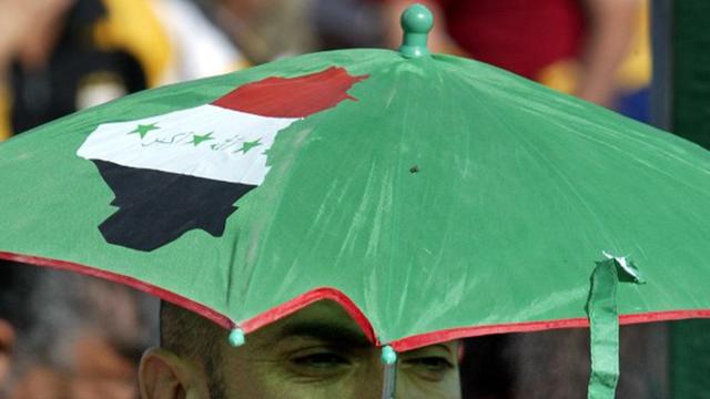 Ein irakischer Shiit trägt einen Schirm mit dem Umirssen des Iraks.