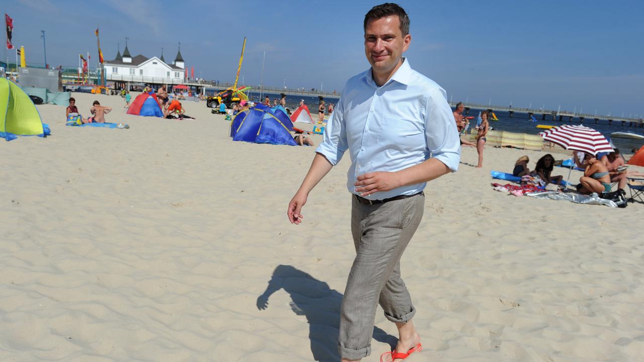 Der SPD-Spitzenkandidat zur Landtagswahl in Sachsen, Martin Dulig, geht am 09.08.2014 mit aufgekrempelter Hose und in roten Badesandalen am Strand vor der Seebrücke von Ahlbeck (Mecklenburg-Vorpommern) entlang.