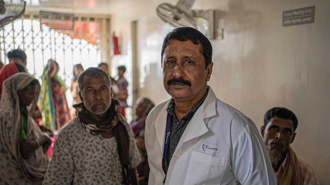 Shaiful Azam steht im weißen Kittel im Wartebereich des Krankenhausboot, im Hintergrund Patienten