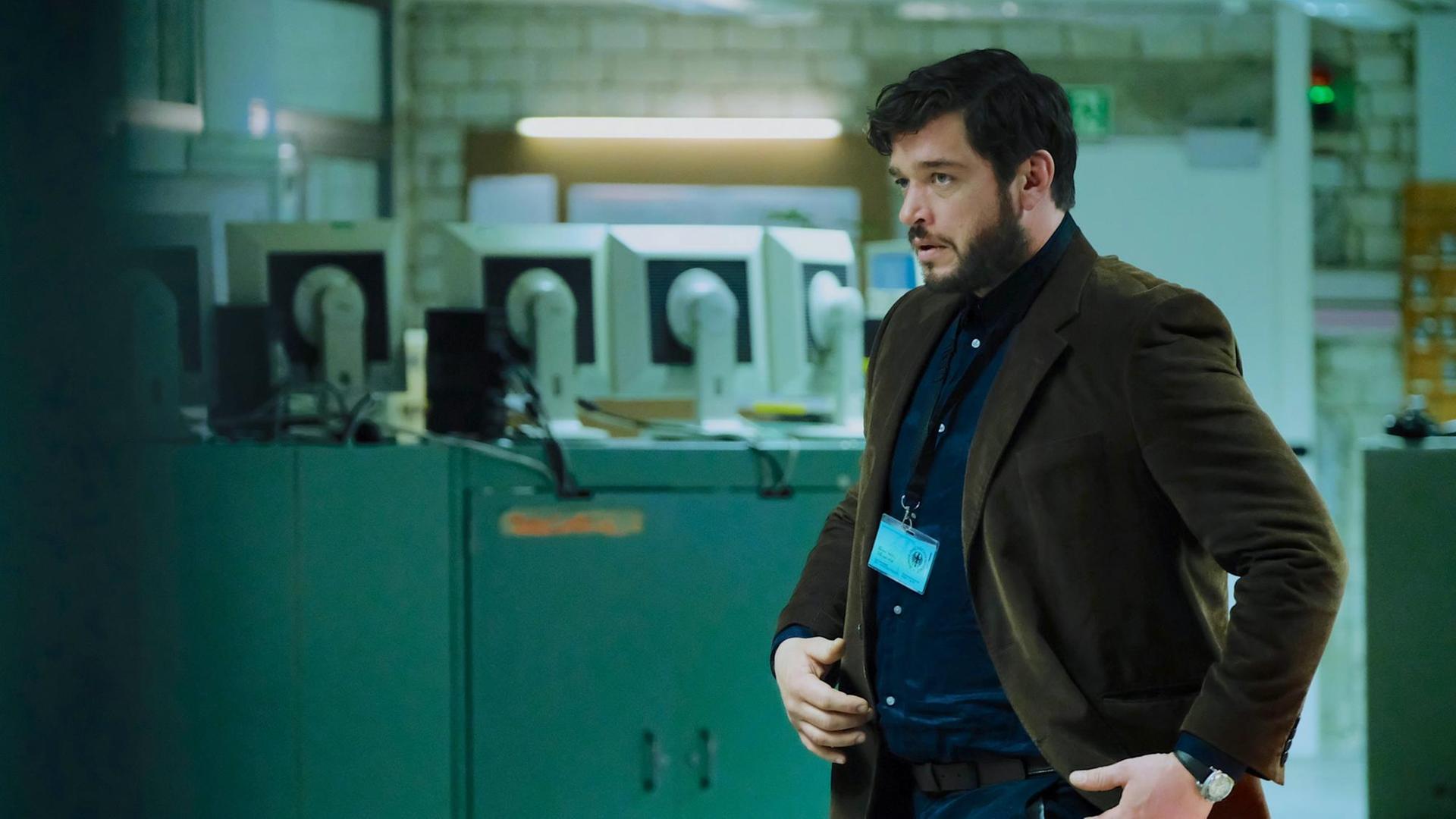 Martin Behrens (Ronald Zehrfeld) in einer Szene des Films "Das Ende der Wahrheit": Er steht in einem Raum mit Computermonitoren und blickt skeptisch. Martin Behrens (Ronald Zehrfeld) in einer Szene des Films "Das Ende der Wahrheit": Er steht in einem Raum mit Computermonitoren und blickt skeptisch.