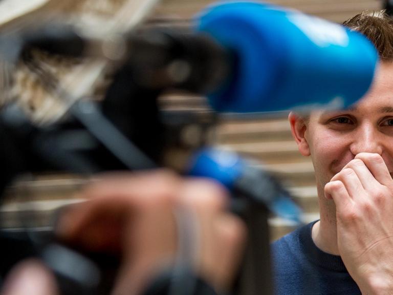 Der österreichische Datenaktivist Max Schrems vor Journalisten. Er lacht.