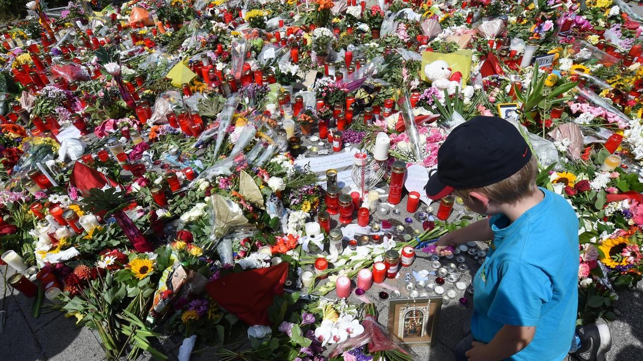 Ein Junge zündet am 24. Juli vor dem Olympia Einkaufszentrum in München eine Kerze für die Opfer des Amoklaufs an. Ein Junge zündet am 24. Juli vor dem Olympia Einkaufszentrum in München eine Kerze für die Opfer des Amoklaufs an.