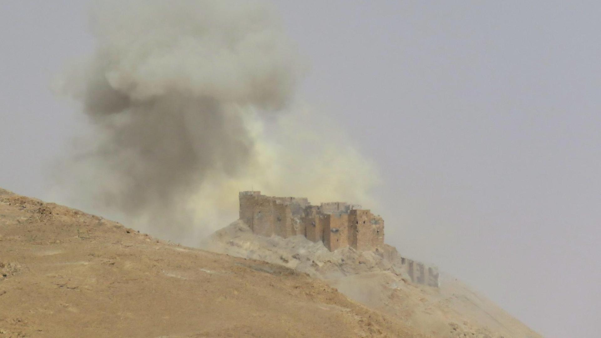 Rauch steigt während der Offensive von syrischen Regierungstruppen aus der Zitadelle von Palmyra auf. Rauch steigt während der Offensive von syrischen Regierungstruppen aus der Zitadelle von Palmyra auf.