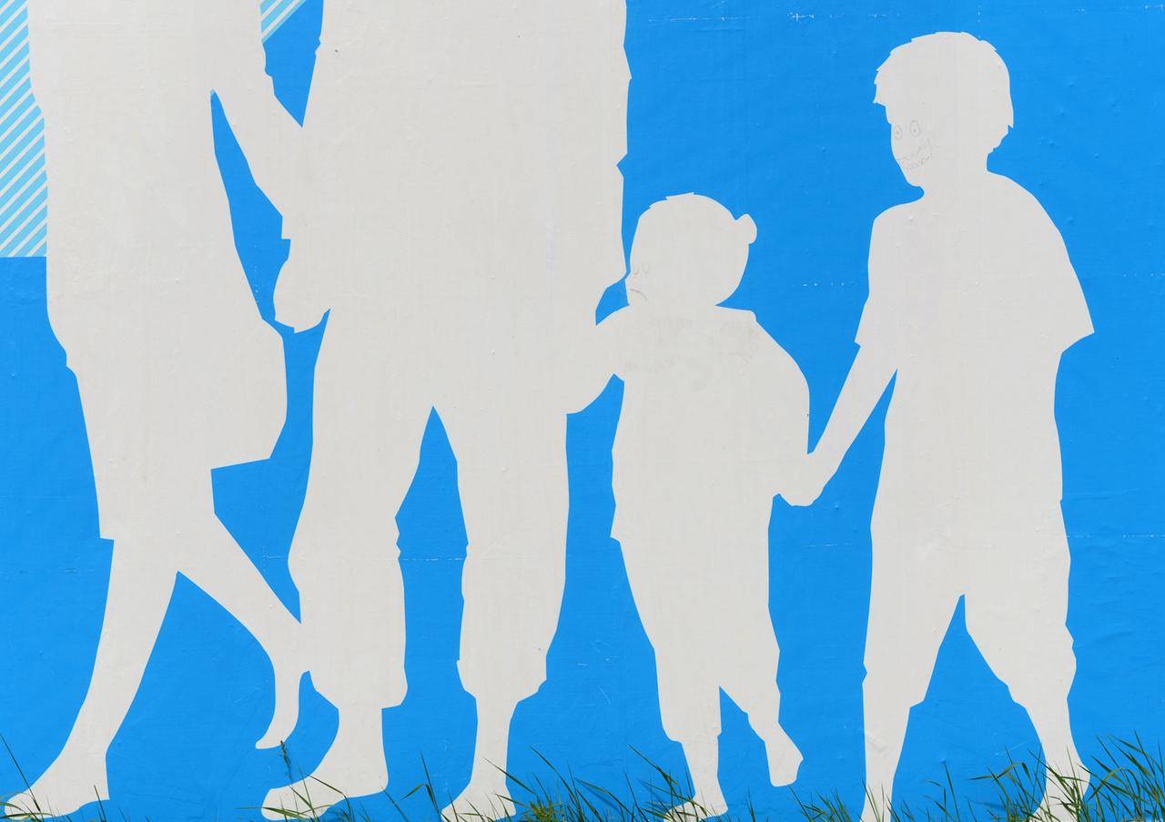 Auf blauem Hintergrund sind die Silhouetten einer Familie mit Mutter, Vater, Tochter und Sohn in weiß zu sehen. Auf blauem Hintergrund sind die Silhouetten einer Familie mit Mutter, Vater, Tochter und Sohn in weiß zu sehen.