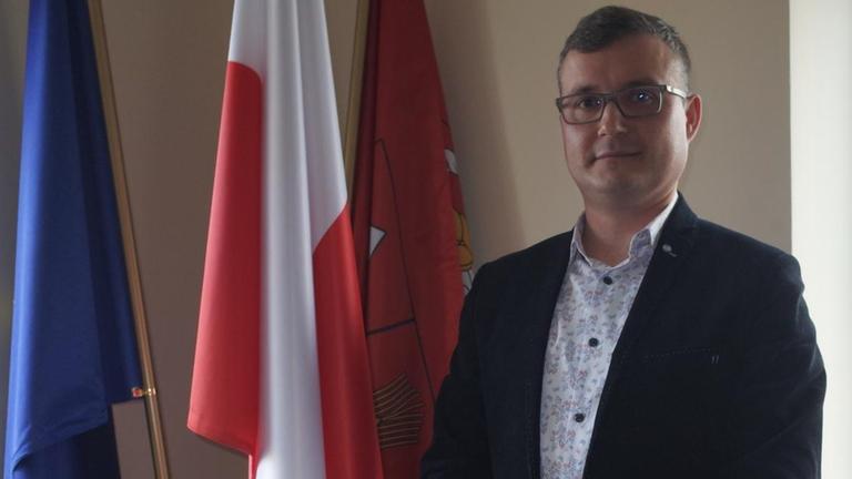 Portrait eines Mannes im Büro, im Hintergrund Flagge EU und Polen Portrait eines Mannes im Büro, im Hintergrund Flagge EU und Polen