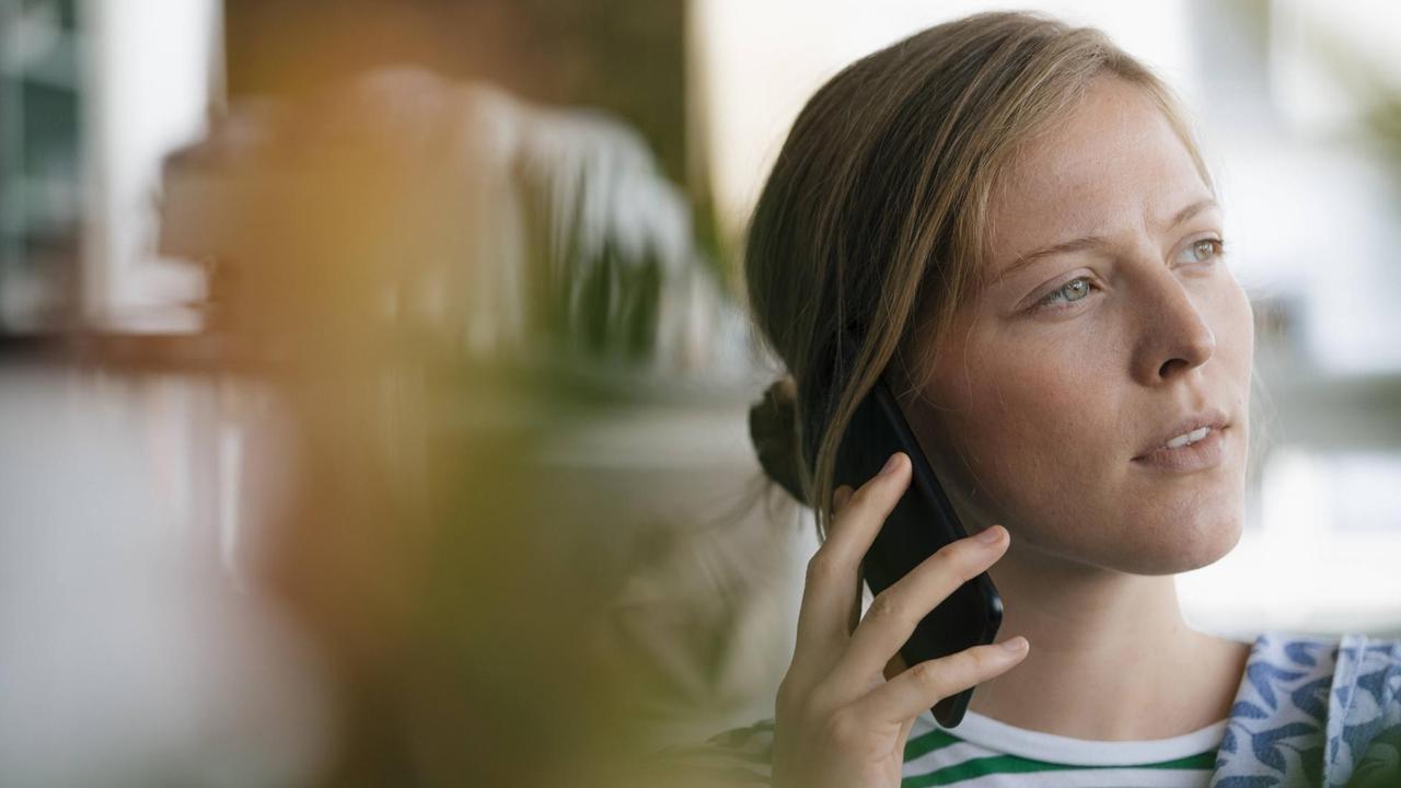 Eine junge Frau sitzt in einem Kaffee und telefoniert. Eine junge Frau sitzt in einem Kaffee und telefoniert.