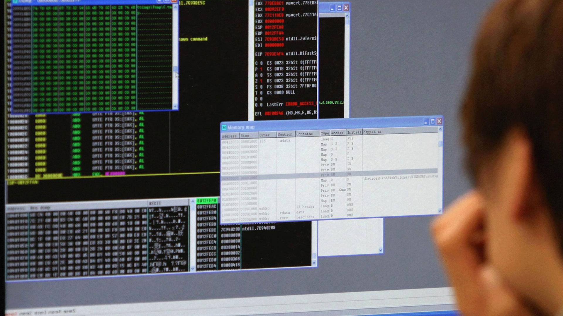 Ein Mann sitzt vor einem Computerbildschirm mit verschiedenen geöffneten Fenstern. Ein Mann sitzt vor einem Computerbildschirm mit verschiedenen geöffneten Fenstern.