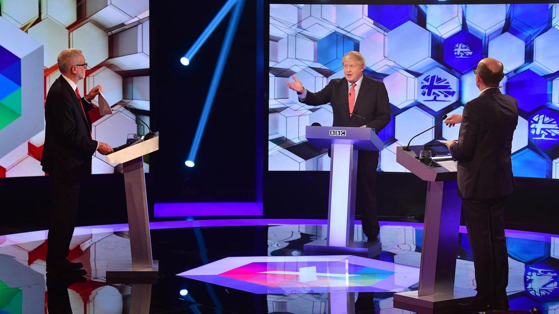 Der Britische Premierminister und Parteichef der Konvervativen Boris Johnson (mitte) bei einer Wahlkampf-TV-Debatte in der BBC mit Labour-Chef Jeremy Corbyn (links). Der Britische Premierminister und Parteichef der Konvervativen Boris Johnson (mitte) bei einer Wahlkampf-TV-Debatte in der BBC mit Labour-Chef Jeremy Corbyn (links).