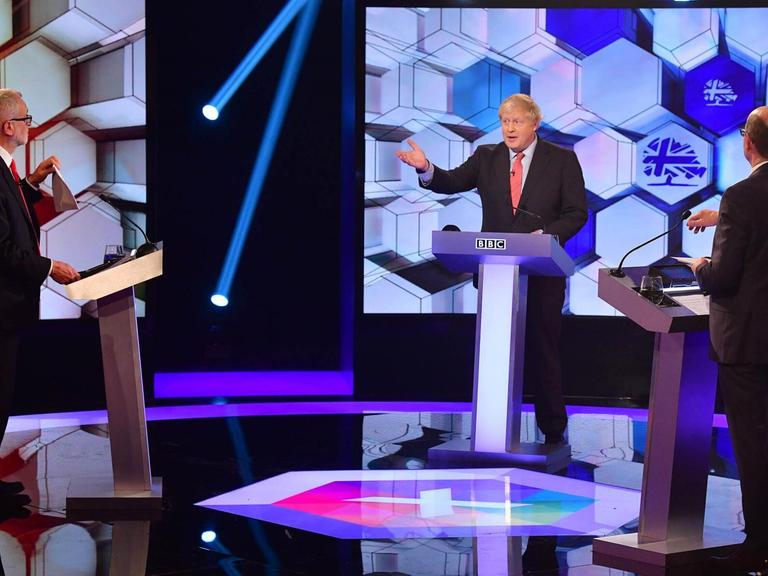 Der Britische Premierminister und Parteichef der Konvervativen Boris Johnson (mitte) bei einer Wahlkampf-TV-Debatte in der BBC mit Labour-Chef Jeremy Corbyn (links).