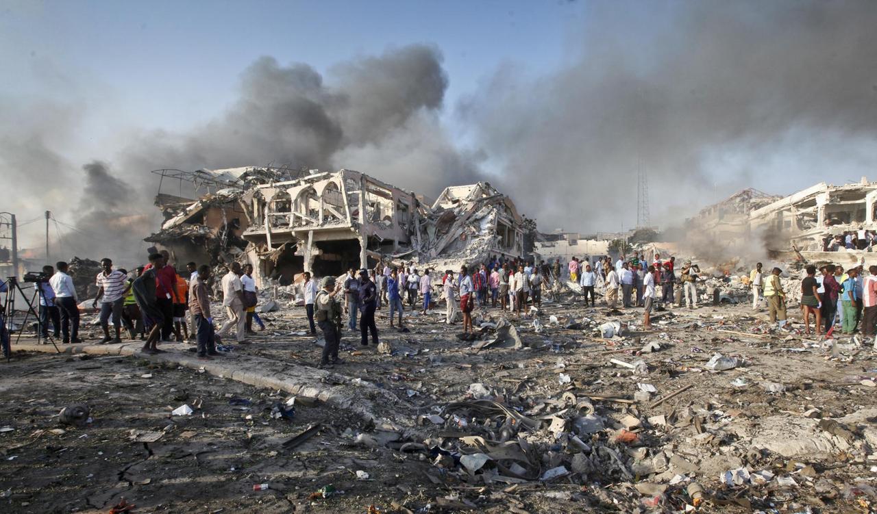 Menschen suchen am in Mogadischu (Somalia) nach einem Selbstmordanschlag in den Trümmern eines Hauses nach Überlebenden. Über ihnen sind Rauchsäulen ztu sehen. Menschen suchen am in Mogadischu (Somalia) nach einem Selbstmordanschlag in den Trümmern eines Hauses nach Überlebenden. Über ihnen sind Rauchsäulen ztu sehen.