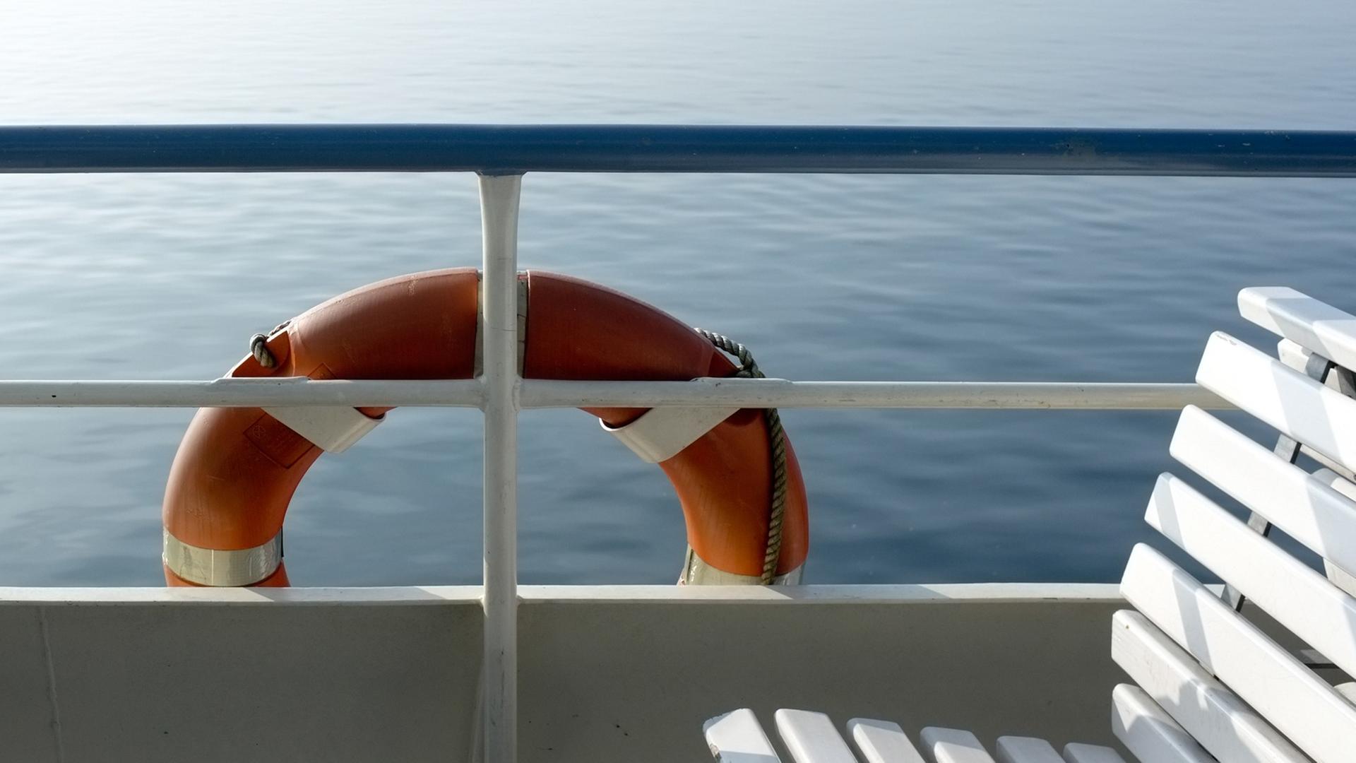 Ein Rettungsring hängt vor einer Sitzbank außen an einem Boot. Ein Rettungsring hängt vor einer Sitzbank außen an einem Boot.