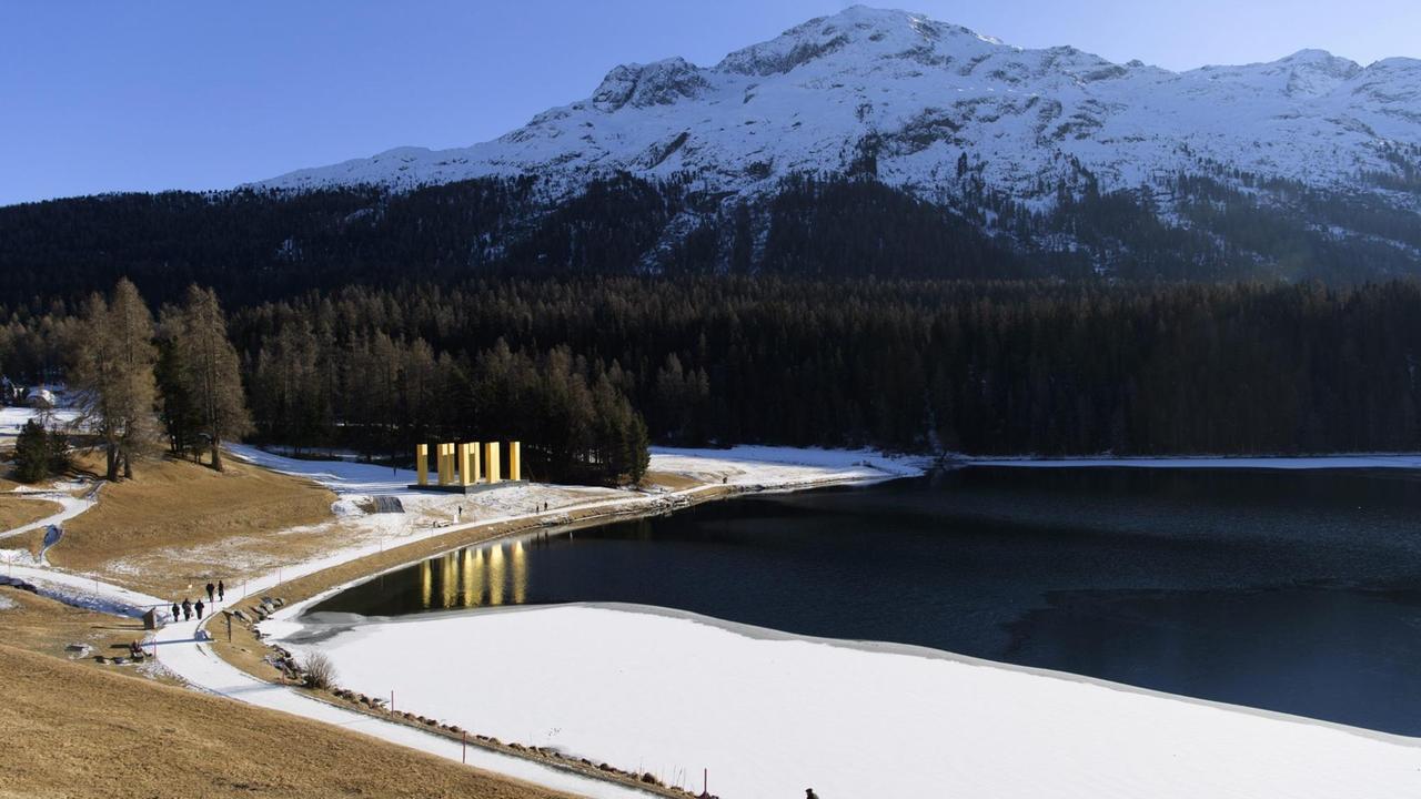 Neun goldene Säulen vor einem Bergpanorama an einem See. Neun goldene Säulen vor einem Bergpanorama an einem See.