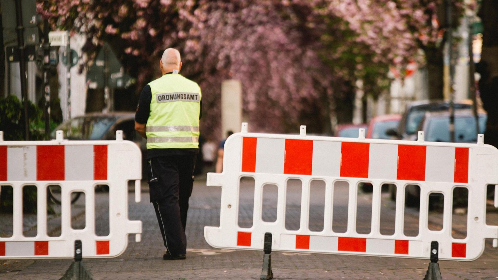 Ein Mitarbeiter des Ordnungsamt Bonn steht vor einer Absperrung. Ein Mitarbeiter des Ordnungsamt Bonn steht vor einer Absperrung.