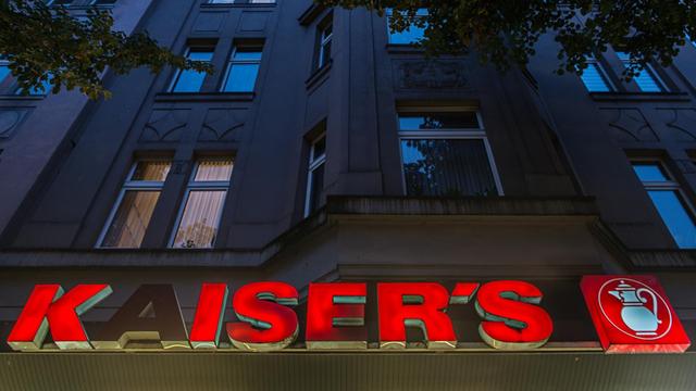 Die Leuchtbuchstaben einer Kaiser's-Filiale hängen in Düsseldorf an einem Gebäude.