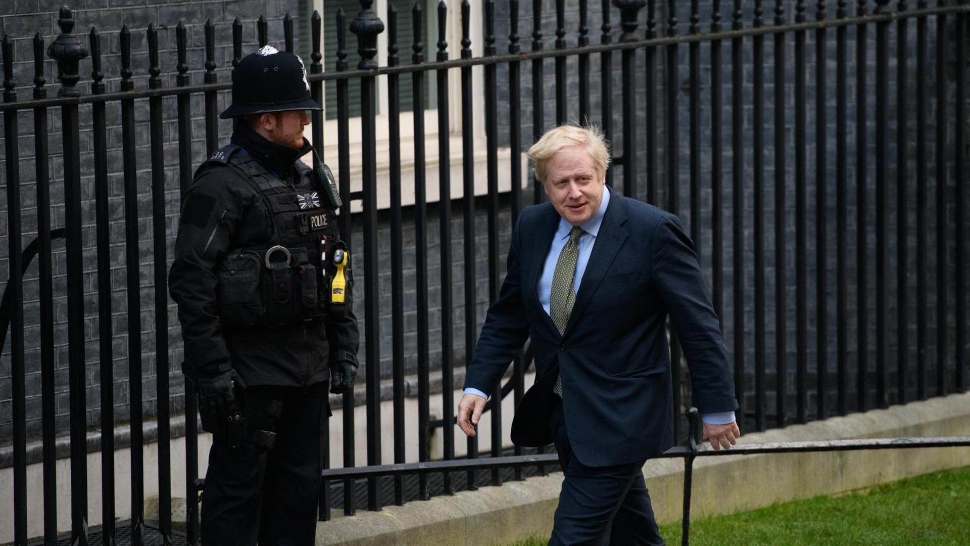 Premierminister Boris Johnson läuft vor Downing Street 10 an einem Wachpolizisten vorbei. Premierminister Boris Johnson läuft vor Downing Street 10 an einem Wachpolizisten vorbei.
