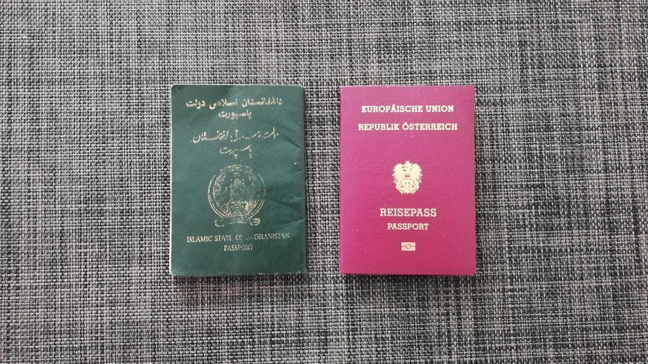 Ein afghanischer und ein österreichischer Pass liegen nebeneinander. Ein afghanischer und ein österreichischer Pass liegen nebeneinander.